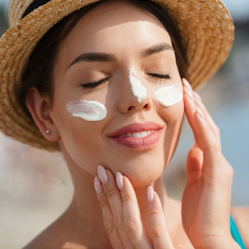 Woman applying sunscreen on her face at the beach